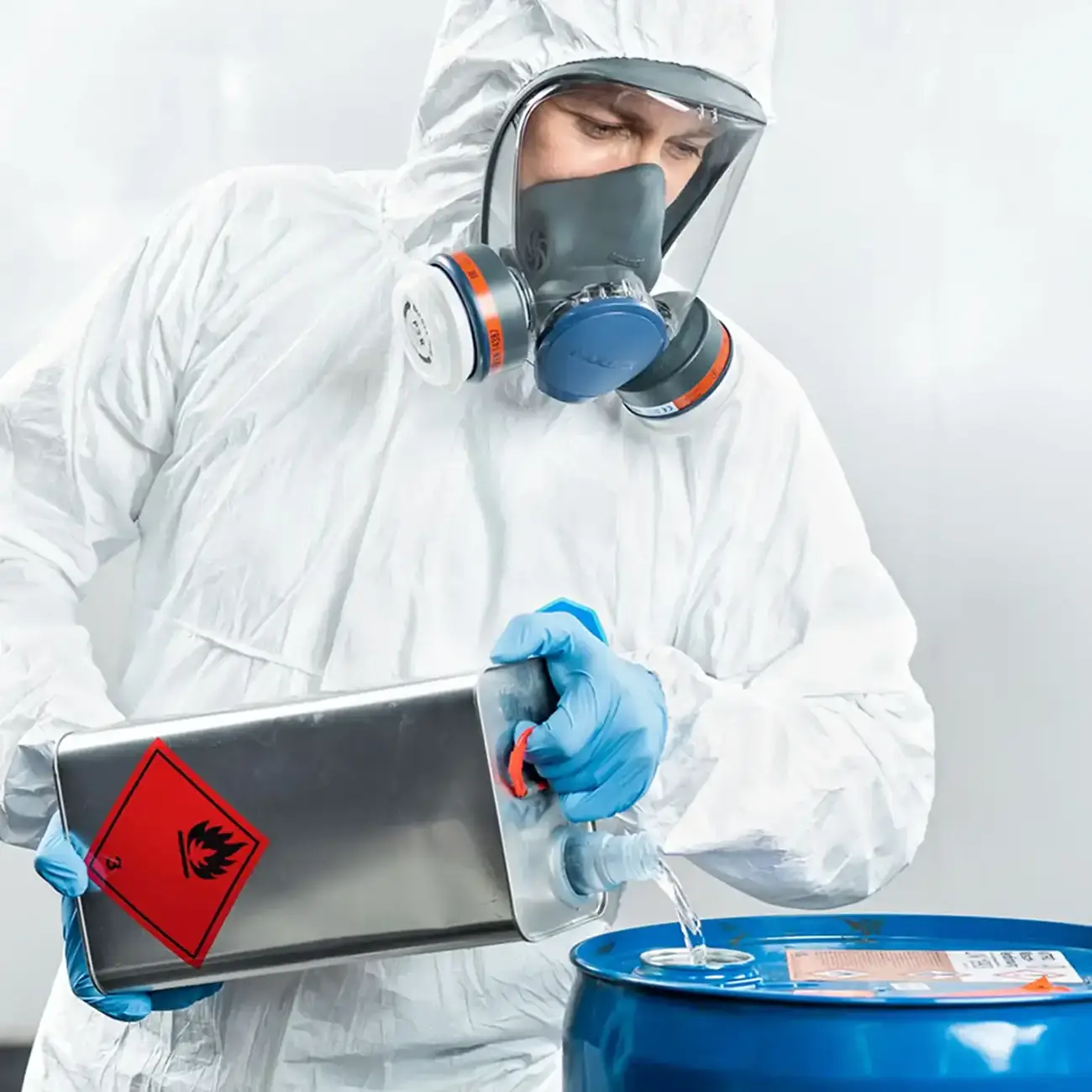 Industriearbeiter beim Arbeiten mit Chemikalien in Schutzkleidung und mit Atemschutz-Vollgesichtsmaske