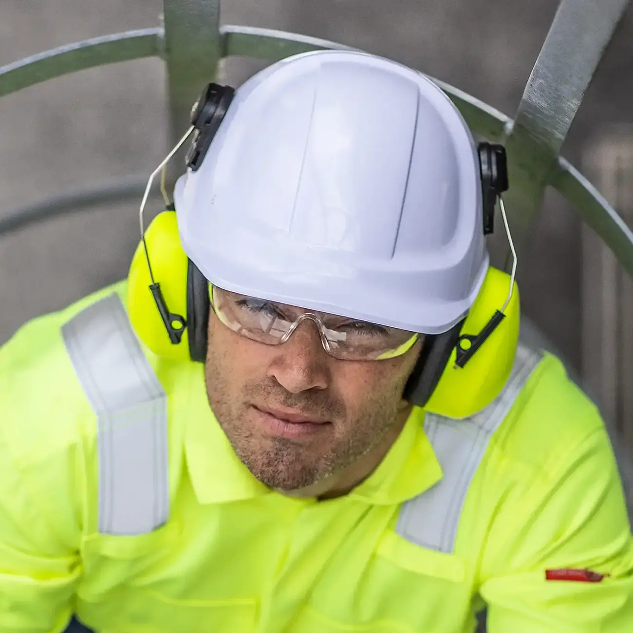 Industriearbeiter mit Helm, Gehörschutz und Warnschutzkleidung