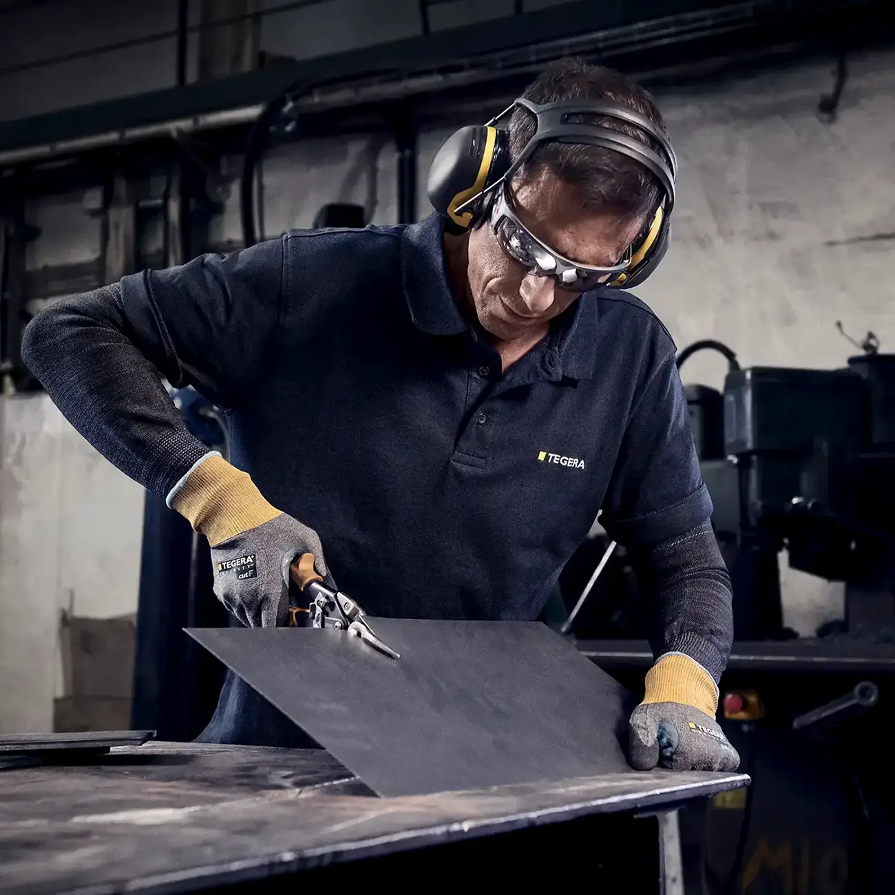 Arbeiter beim Schneiden von Blech mit Schnittschutzhandschuhen 